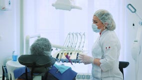 Hälsa och tandvård, kvinna på arbete som tandläkare och doktor som talar till en manlig patient Diskutera tand- behandling in stock video Hälsa och tandvård, kvinna på arbete som tandläkare och doktor som talar till en manlig patient Diskutera tand- behandling in stock video