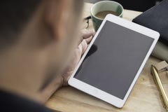 Hände eines Mannes, der leeres Tablettengerät über einer hölzernen Arbeitsplatztabelle hält stockbilder Hände eines Mannes, der leeres Tablettengerät über einer hölzernen Arbeitsplatztabelle hält stockbilder