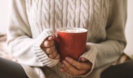 Händer för kvinna` s i tröja rymmer koppen av varmt kaffe, choklad eller te Begreppsvinterkomfort, dricka för morgon som är varmt royaltyfri fotografi Händer för kvinna` s i tröja rymmer koppen av varmt kaffe, choklad eller te Begreppsvinterkomfort, dricka för morgon som är varmt royaltyfri fotografi