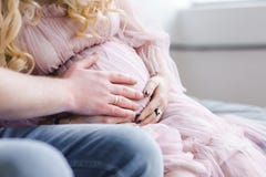 Händer för man` s på buken av en gravid flicka förvänta ett barn som förbereder sig för barnsbörd förälskelse av fadern till barn arkivbild Händer för man` s på buken av en gravid flicka förvänta ett barn som förbereder sig för barnsbörd förälskelse av fadern till barn arkivbild