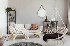Hängande stol och soffa i ethnovardagsruminre med den runda spegeln Verkligt foto arkivfoto Hängande stol och soffa i ethnovardagsruminre med den runda spegeln Verkligt foto arkivfoto