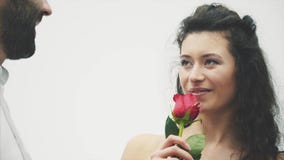 Härlig elegant grabb i en klassisk skjorta med röda rosor i hans händer Syns på en vit bakgrund Ger rosorna till Härlig elegant grabb i en klassisk skjorta med röda rosor i hans händer Syns på en vit bakgrund Ger rosorna till