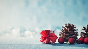 Härlig enkel julbakgrund med kopieringsutrymme Gullig julklapp röda prydnader och att sörja kottar på blå bakgrund royaltyfria bilder Härlig enkel julbakgrund med kopieringsutrymme Gullig julklapp röda prydnader och att sörja kottar på blå bakgrund royaltyfria bilder