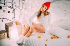 Härlig flicka i en röd hatt med pomponen som sitter nära julsammansättning bland mandarines och apelsiner royaltyfria bilder Härlig flicka i en röd hatt med pomponen som sitter nära julsammansättning bland mandarines och apelsiner royaltyfria bilder