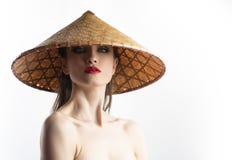 Härlig flickamodell med rött kantsmink och nakna skuldror som bär den asiatiska vietnamesiska kottehatten som göras av rottingen royaltyfri foto Härlig flickamodell med rött kantsmink och nakna skuldror som bär den asiatiska vietnamesiska kottehatten som göras av rottingen royaltyfri foto