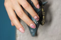 Härlig kvinnlig hand med manikyr Ljus - rosa färger spikar polermedel med idérik design Kanter och glassklistermärkear royaltyfria bilder Härlig kvinnlig hand med manikyr Ljus - rosa färger spikar polermedel med idérik design Kanter och glassklistermärkear royaltyfria bilder