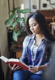 Härlig latinamerikansk kvinna som läser en pappers- bok fotografering för bildbyråer Härlig latinamerikansk kvinna som läser en pappers- bok fotografering för bildbyråer