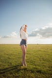 Härlig och attraktiv kvinna med sexiga ben på grässkon som håller ögonen på mindre solen med hennes hand ovanför henne ögon royaltyfria bilder Härlig och attraktiv kvinna med sexiga ben på grässkon som håller ögonen på mindre solen med hennes hand ovanför henne ögon royaltyfria bilder