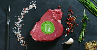 Härlig saftig biff för nytt kött på en tabell med salt, rosmarin, vitlök och tomaten på en svart bakgrund, bästa sikt Begrepp: fr fotografering för bildbyråer Härlig saftig biff för nytt kött på en tabell med salt, rosmarin, vitlök och tomaten på en svart bakgrund, bästa sikt Begrepp: fr fotografering för bildbyråer