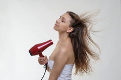 Härlig ung flicka med fantastiskt långt brunetthår i en vit damunderkläder som poserar med en slaghårtork på vit bakgrund royaltyfria bilder Härlig ung flicka med fantastiskt långt brunetthår i en vit damunderkläder som poserar med en slaghårtork på vit bakgrund royaltyfria bilder