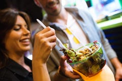 Härligt besöka för ung kvinna äter marknaden och att äta färgrik sallad i gatan arkivfoto Härligt besöka för ung kvinna äter marknaden och att äta färgrik sallad i gatan arkivfoto