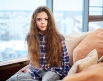 Härligt liten flickasammanträde på en soffa arkivfoton Härligt liten flickasammanträde på en soffa arkivfoton