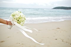 Hållande bröllopbukett för hand med strandbakgrund royaltyfria bilder Hållande bröllopbukett för hand med strandbakgrund royaltyfria bilder