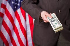 Hållande dollar för affärsman bredvid flagga arkivfoto Hållande dollar för affärsman bredvid flagga arkivfoto
