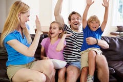 Hållande ögonen på fotboll för familj på TV som firar mål royaltyfri fotografi Hållande ögonen på fotboll för familj på TV som firar mål royaltyfri fotografi