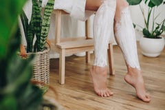 Hårborttagningsbegrepp, depilationkräm Ung kvinna i den vita handduken som applicerar raka kräm på hennes ben i hem- badrum med g fotografering för bildbyråer Hårborttagningsbegrepp, depilationkräm Ung kvinna i den vita handduken som applicerar raka kräm på hennes ben i hem- badrum med g fotografering för bildbyråer
