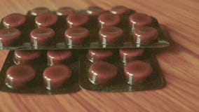 Hög av kapslar som packas i blåsor, rund mönstrad formad medicinminnestavla eller antibiotiska piller på trätabellbakgrund Medica Hög av kapslar som packas i blåsor, rund mönstrad formad medicinminnestavla eller antibiotiska piller på trätabellbakgrund Medica
