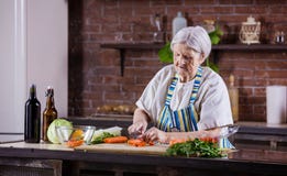 Hög kvinna som hugger av nya grönsaker för sallad royaltyfri fotografi Hög kvinna som hugger av nya grönsaker för sallad royaltyfri fotografi