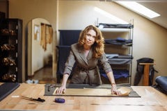 Hübscher fokussierter Modedesigner der jungen Frau, der weißes Gewebe im Studio schneidet stockfoto Hübscher fokussierter Modedesigner der jungen Frau, der weißes Gewebe im Studio schneidet stockfoto