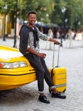 H?bscher Reisender des jungen Mannes mit Gep?ck und h?hlen einen Kaffee, der auf einem gelben Haubentaxi vom Flughafen setzt Vert lizenzfreies stockfoto H?bscher Reisender des jungen Mannes mit Gep?ck und h?hlen einen Kaffee, der auf einem gelben Haubentaxi vom Flughafen setzt Vert lizenzfreies stockfoto