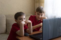 I due fratelli stanno sedendo nel salone e stanno giocando con il pc fotografia stock libera da diritti I due fratelli stanno sedendo nel salone e stanno giocando con il pc fotografia stock libera da diritti