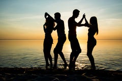 I giovani, studenti stanno ballando sulla spiaggia al backgr del tramonto immagine stock I giovani, studenti stanno ballando sulla spiaggia al backgr del tramonto immagine stock
