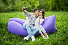 I love you too much. Young couple kissing sitting on inflatable sofa lamzac and take selfie on phone while resting on grass in par stock images I love you too much. Young couple kissing sitting on inflatable sofa lamzac and take selfie on phone while resting on grass in par stock images