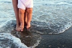 I piedi del bambino e della madre al mare spumano immagini stock libere da diritti I piedi del bambino e della madre al mare spumano immagini stock libere da diritti