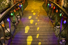 Idea innovadora de los rastros del pie humano en el camino de madera con las luces coloridas que cuelgan en las verjas Gema ocult imagen de archivo Idea innovadora de los rastros del pie humano en el camino de madera con las luces coloridas que cuelgan en las verjas Gema ocult imagen de archivo