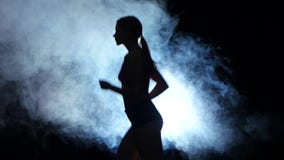 Idrotts- konditionflickaspring på en svart bakgrund som är upplyst vid strålkastaren i röken silhouette arkivfilmer Idrotts- konditionflickaspring på en svart bakgrund som är upplyst vid strålkastaren i röken silhouette arkivfilmer