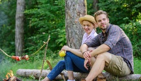 Idyllic picnic date. Couple in love relaxing sit on log having snacks. Family enjoy weekend in nature. Picnic roasting stock photo Idyllic picnic date. Couple in love relaxing sit on log having snacks. Family enjoy weekend in nature. Picnic roasting stock photo