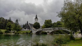 Iglesia y puente en el lago Bohinj en Eslovenia Día muy nublado fotografía de archivo Iglesia y puente en el lago Bohinj en Eslovenia Día muy nublado fotografía de archivo