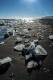 Ijsstukken bij een zwart strand met vulkanisch zand stock afbeelding Ijsstukken bij een zwart strand met vulkanisch zand stock afbeelding