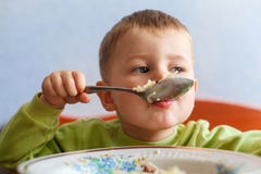 Il bambino affamato mangia il pranzo con grande appetito Il ragazzo sveglio mangia la pasta immagine stock Il bambino affamato mangia il pranzo con grande appetito Il ragazzo sveglio mangia la pasta immagine stock