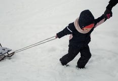 Il bambino sta trascinando la slitta immagine stock Il bambino sta trascinando la slitta immagine stock