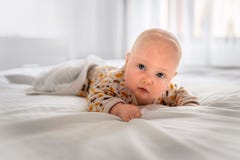 Il bambino sta trovandosi sul letto bianco immagine stock libera da diritti Il bambino sta trovandosi sul letto bianco immagine stock libera da diritti