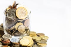 Il barattolo di soldi, varia valuta conia lo straripamento sul fondo bianco fotografia stock Il barattolo di soldi, varia valuta conia lo straripamento sul fondo bianco fotografia stock