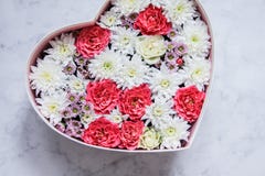 Il contenitore di regalo con cuore ha modellato i fiori su fondo di marmo grigio immagine stock libera da diritti Il contenitore di regalo con cuore ha modellato i fiori su fondo di marmo grigio immagine stock libera da diritti