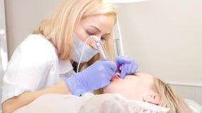 Il cosmetologo di medico fa la procedura di trucco permanente per le labbra femminili del cliente 4K video d archivio Il cosmetologo di medico fa la procedura di trucco permanente per le labbra femminili del cliente 4K video d archivio