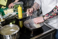 Il cuoco unico prepara l'halibut sotto sedano nella cucina del ristorante immagine stock Il cuoco unico prepara l'halibut sotto sedano nella cucina del ristorante immagine stock