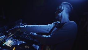 Il DJ in cuffie che mescolano musica sulla piattaforma girevole al partito del night-club Stile di Doodle archivi video Il DJ in cuffie che mescolano musica sulla piattaforma girevole al partito del night-club Stile di Doodle archivi video
