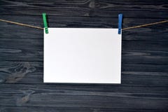 Il foglio di carta bianco si è fissato con una molletta da bucato su una parete di legno fotografie stock Il foglio di carta bianco si è fissato con una molletta da bucato su una parete di legno fotografie stock