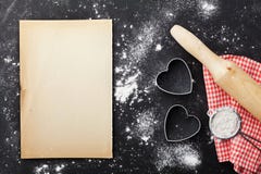 Il fondo di cottura con farina, il matterello, lo strato di carta ed il cuore modellano sulla tavola del nero della cucina da sop fotografia stock libera da diritti Il fondo di cottura con farina, il matterello, lo strato di carta ed il cuore modellano sulla tavola del nero della cucina da sop fotografia stock libera da diritti