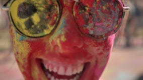 Il fronte di giovane ragazza felice in polvere colourful con gli occhiali da sole sta sorridendo sul festival di holi di giorno d stock footage Il fronte di giovane ragazza felice in polvere colourful con gli occhiali da sole sta sorridendo sul festival di holi di giorno d stock footage
