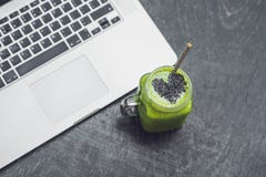 Il frullato verde fresco con la banana e gli spinaci con cuore dei semi di sesamo e di un computer portatile amano per un concett Immagine Stock Libera da Diritti Il frullato verde fresco con la banana e gli spinaci con cuore dei semi di sesamo e di un computer portatile amano per un concett Immagine Stock Libera da Diritti