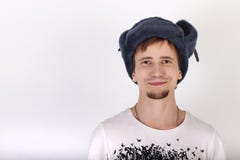 Il giovane bello felice in cappuccio grigio con i earflaps sorride immagini stock Il giovane bello felice in cappuccio grigio con i earflaps sorride immagini stock