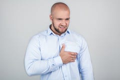 Il giovane bello tiene la mano, essendo stricked dalle notizie terribili, esprime la sensibilità negativa, ha forte attacco di cu fotografie stock Il giovane bello tiene la mano, essendo stricked dalle notizie terribili, esprime la sensibilità negativa, ha forte attacco di cu fotografie stock