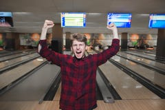 Il giovane felice ha fatto un colpo di bowling Lo studente ha sollevato le sue mani dalla gioia mentre giocava lanciare Vittoria immagini stock Il giovane felice ha fatto un colpo di bowling Lo studente ha sollevato le sue mani dalla gioia mentre giocava lanciare Vittoria immagini stock