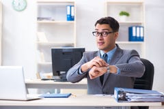 Il giovane impiegato bello dell'uomo d'affari che lavora nell'ufficio allo scrittorio immagini stock Il giovane impiegato bello dell'uomo d'affari che lavora nell'ufficio allo scrittorio immagini stock