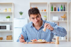 Il giovane marito che mangia alimento insipido a casa per pranzo fotografie stock Il giovane marito che mangia alimento insipido a casa per pranzo fotografie stock